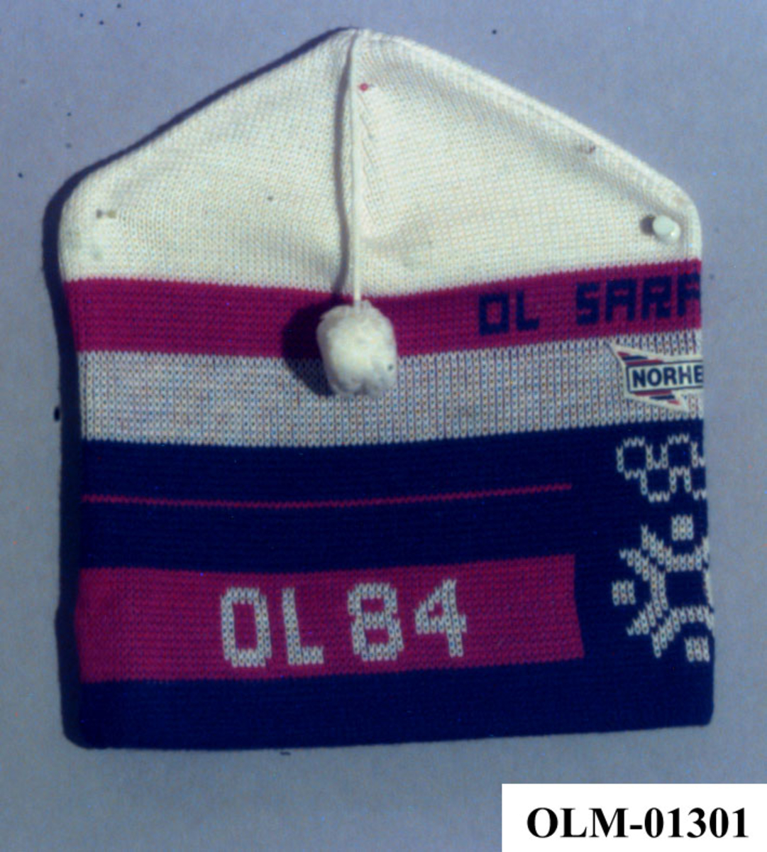 Rød, hvit og blå lue med dusk. På luen er det emblem for de olympiske vinterleker i Sarajevo i 1984 og et påsydd merke med logo for Norheim.