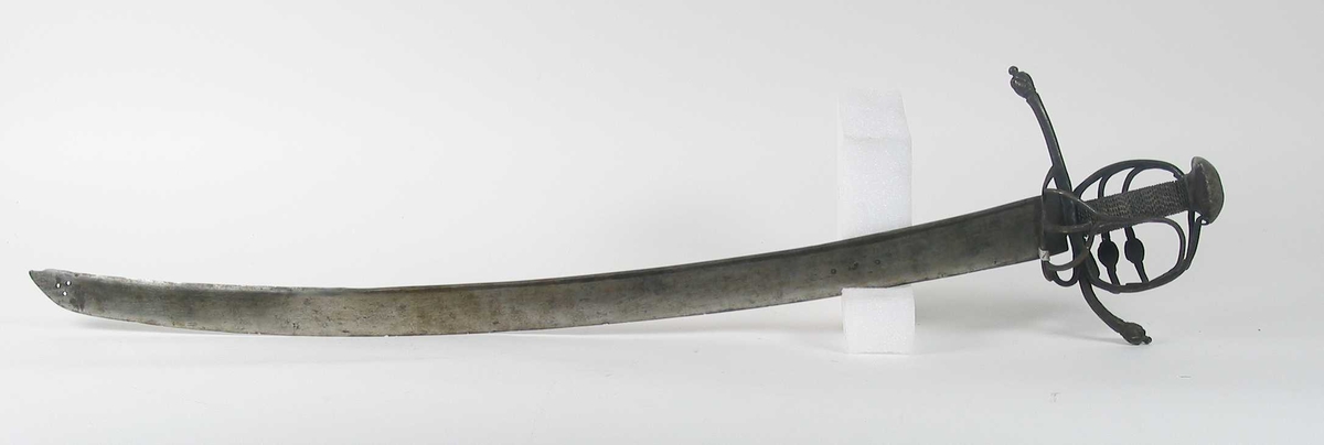 Pyramideformet knapp med strekdekor. Asymmetrisk kurvfeste med to sidebøyler( øverste avbrukket )med riflede fortykkelser på midten. mellom håndbøylen og kurvens ytterkant. Innsiden har en  sidebøyle. Kurvens basis er på utsiden en kvadratisk parérplate med to hjerteformede gjennombrytninger. På innsiden er det en klingebrekker og tommelbøyle. Opp og nedbøyde parérstenger med riflede fortykkelser på endene.
Tregrep med nyere jerntrådvikling.
Enegget krum klinge med 3 hull ipå klingspissen og en smal hulslipning på ryggsiden.Tre smedmerker på venstre side. 