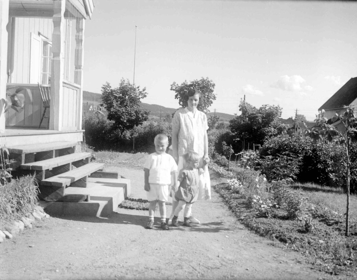 Kvinne med to barn forran veranda. Erika og Gunnar Berge og Odd Jens Bjerke.