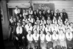 Gruppe med menn, kvinner og barn, trolig skole