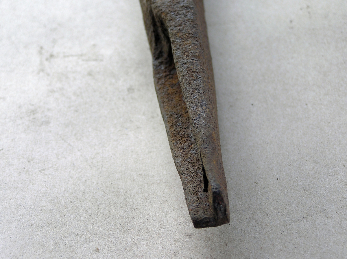 Smidd jernstykke til bruk ved smiing av merkeøks. Merket ble formet rundt stempelet. Stempeldel og håndtak i ett. L-formet stempel. Noe rust.