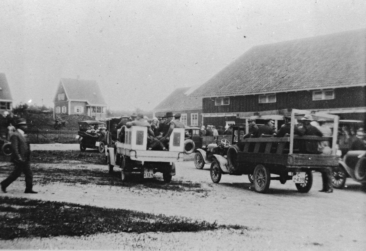 Bikongressen i Ås, juli 1927. 2 lastebiler innrettet for persontransport samt personbiler på et gårdstun. To villaer i bakgrunnen.