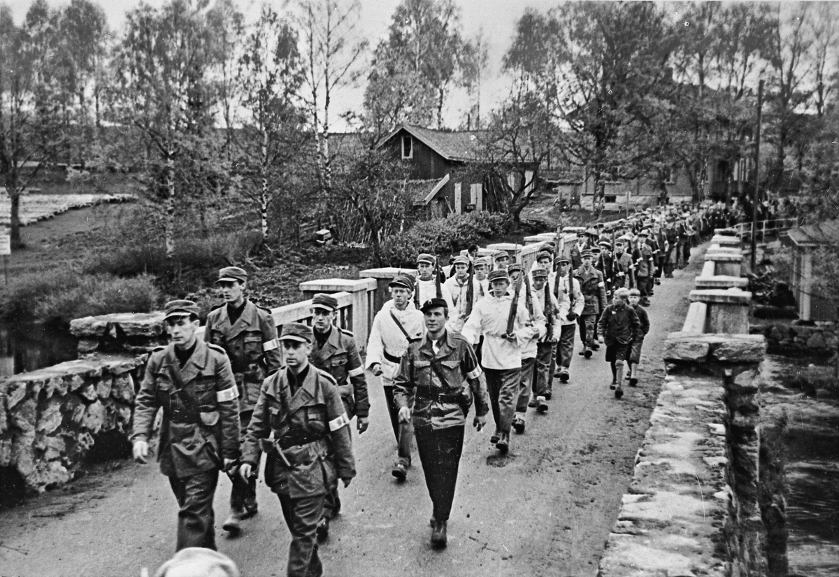 Hjemmestyrkene marsjerer over den gamle brua ved Eidsvollbygningen.