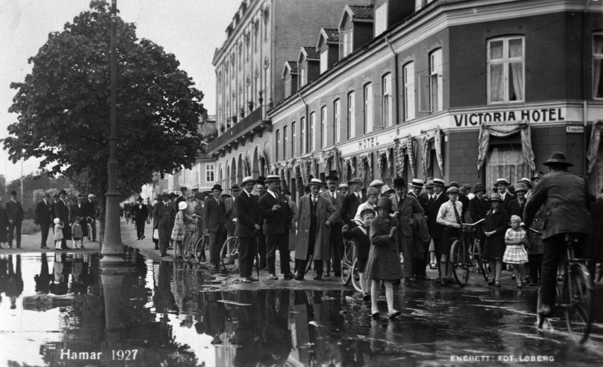 Postkort, Hamar by, flom i Mjøsa, Mjøsflommen 1927, mye folk utenfor Victoria Hotel i Strandgata 21,
