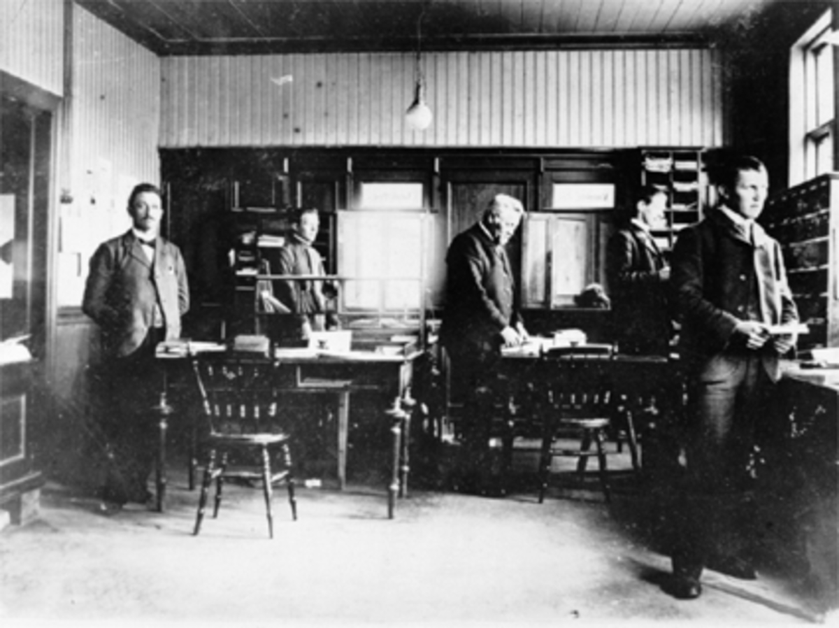 Interiør, Hamar Postkontor, Postmester Hansen, 4 menn. Postkontoret holdt til der Astoria-bygget ved Østre Torg ligger, fra 1901 til 1914. Se 0401-00381 for eksteriør. 