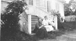 2 damer sitter i trappa foran hovedbygningen på Eik, Helgøya