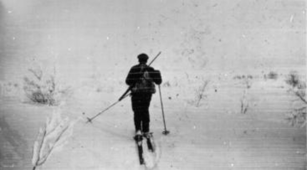 Tor Solbakken på ski med ryggsekk og gevær. Vinterjakt.