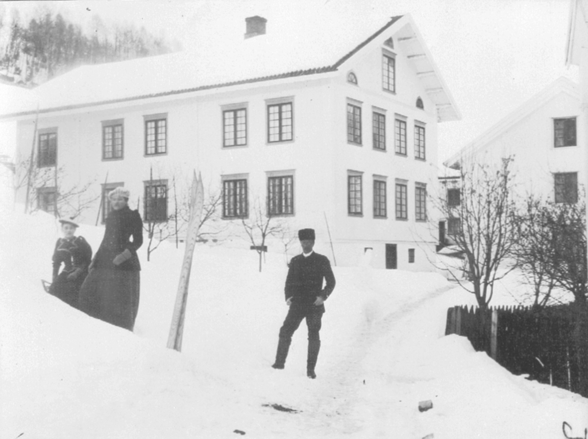To kvinner og en mann foran tjenerboligen på Berg gård, Brøttum, Ringsaker. Utleid i forbindelse med jernbaneutbyggingen.