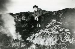 Ingunn Rasmussen (g. Sandtröen) sitter ved et bål, ca 1955