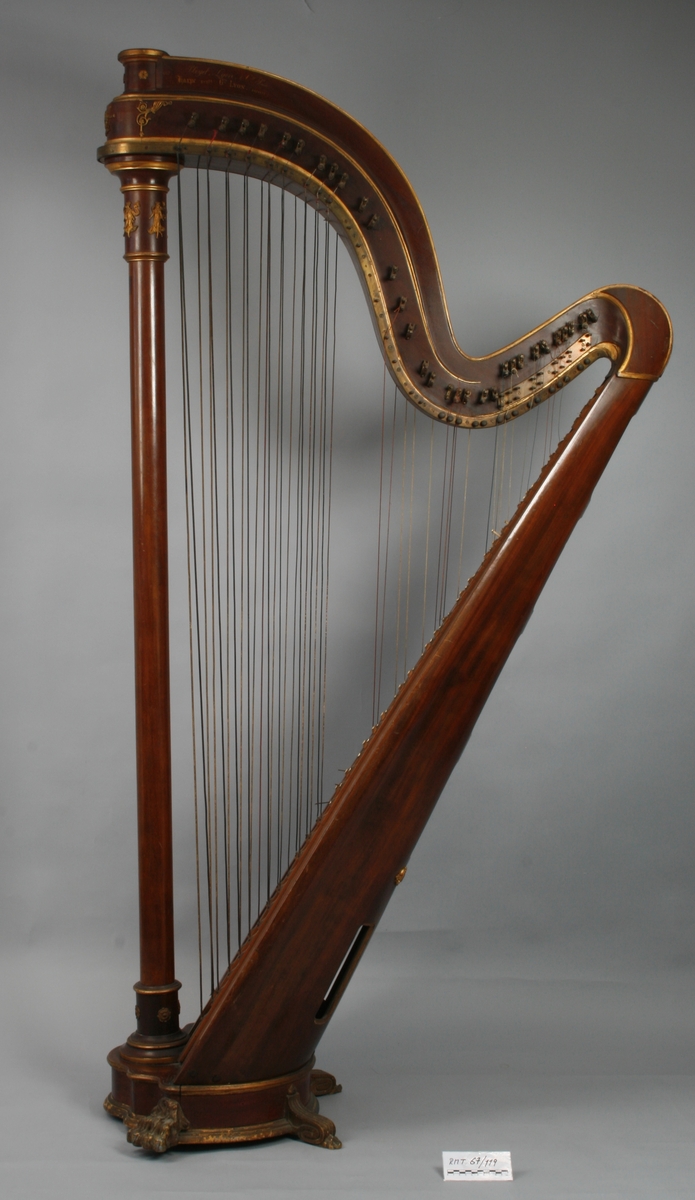 Kromatisk harpe med strengene i to rekker, 31 + 45 strenger. I bunnen 6 rektangulære lydhull med avrundede hjørner og forgylte kanter. Dreid forstang med forgylt metalldekor, bl.a. kvinnefigurer i greske gevanter.