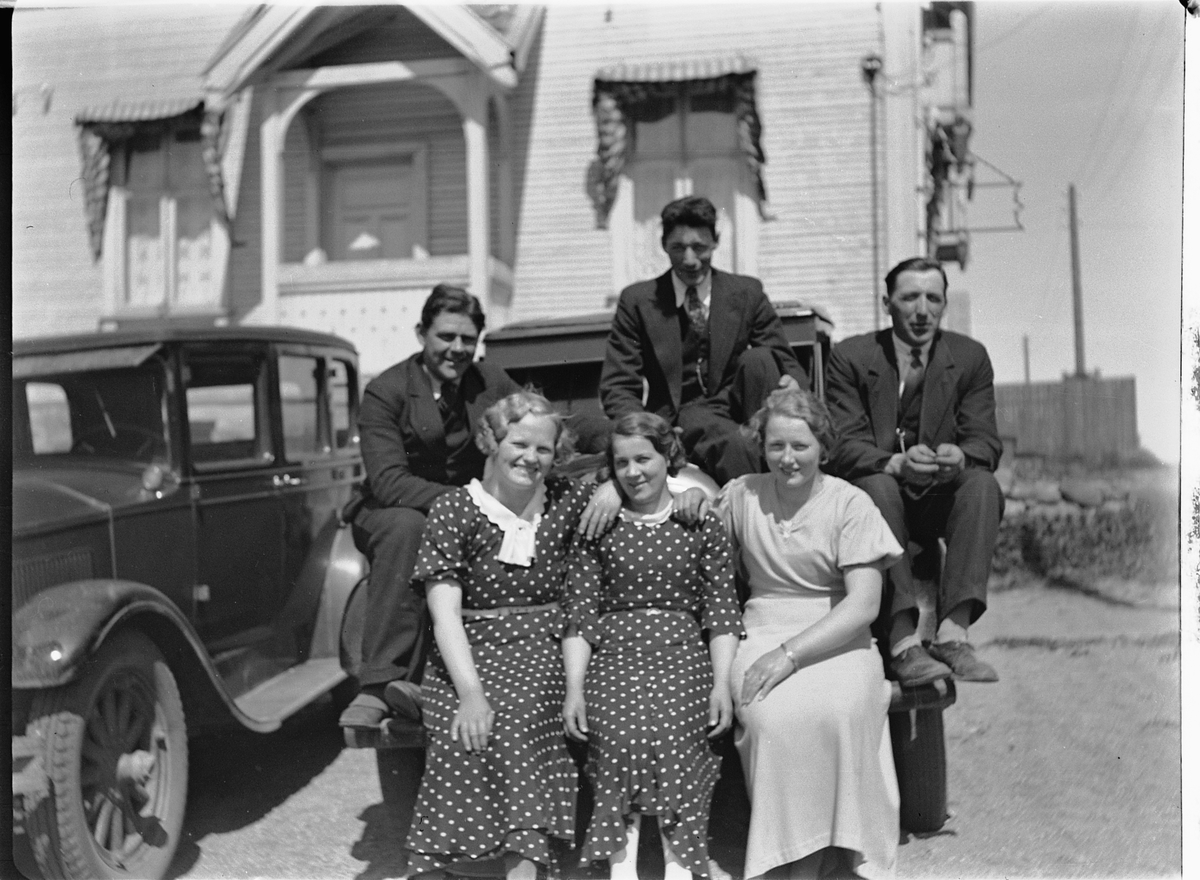 Tre menn og tre kvinner sitter på en bil , muligens en Buick 1926-1928,(Samme situasjon HHB-00919). Den skjulte bilen er bil D-82, en Auburn fra 1925-27. Bildet antas å være fra andre halvdel av 1930-tallet, siden bilnummeret var i bruk på en/flere Ford'er i registreringsbøkene fra 1925, 27, 28, 30 og 35 (Hamar politidistrikt, Vang eller Løten).