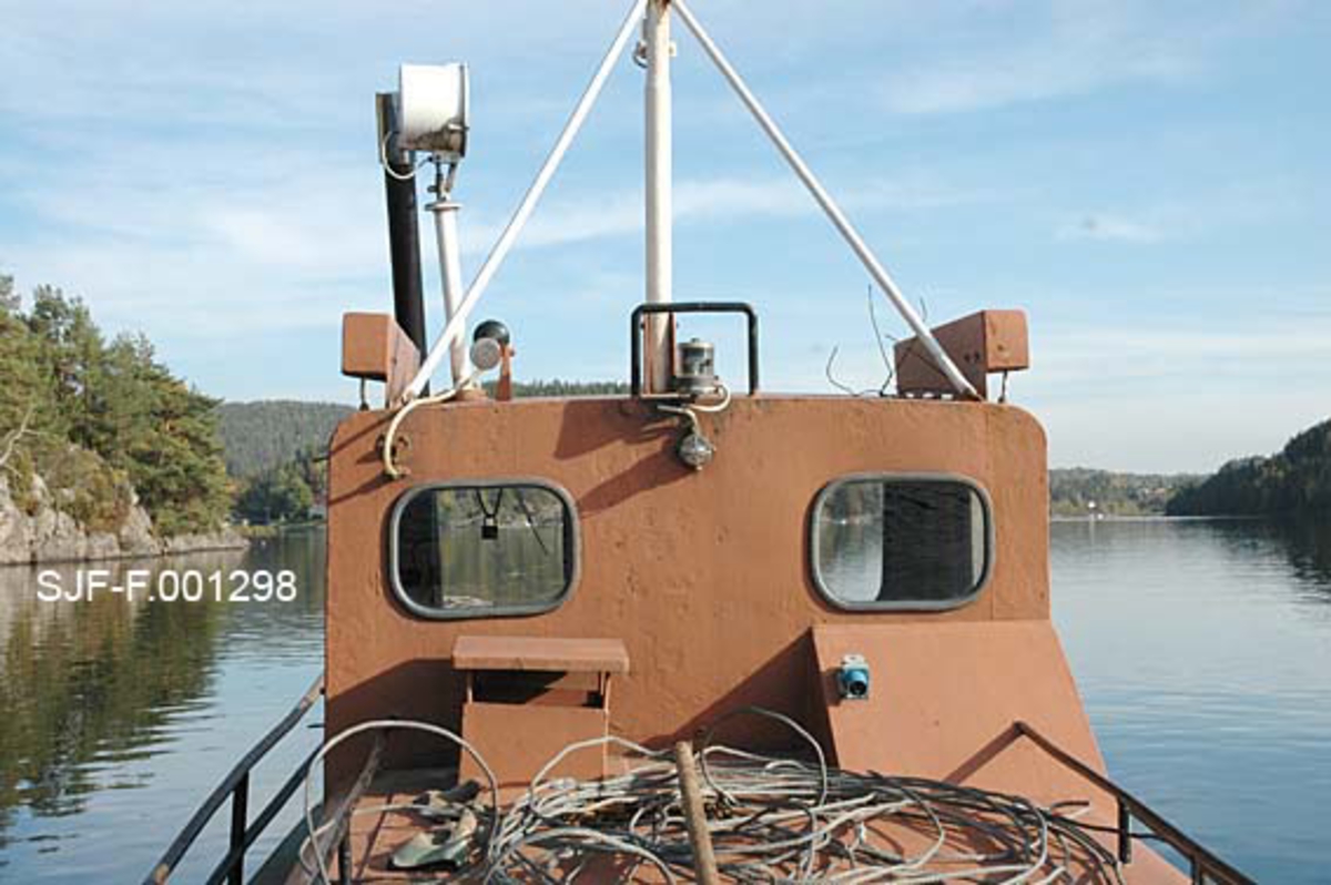 Styrhuset på Skiensvassdragets fellesfløtingsforenings slepebåt Fridtjof.  Båten er malt med en rødbrun farge. På dekket, like foran styrhuset, ligger det en del vaierbunter. 