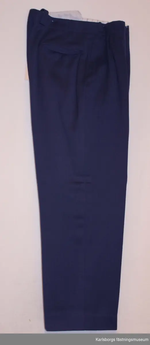 Långbyxa m/1930 tilverks av mörkblå kläde tyg. Försedd med 2 raka sidfickor och en bakficka. Gylfen är försedd med 6 knappar och kanpphål. Midjeband med knappar och knapptamp för hängslen och hällor för bälte.