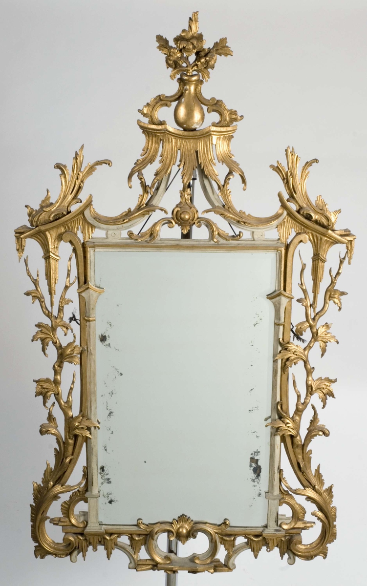 Rektangulært, høyreist speil med 2 speilplater, samt forgylt ramme med utskåret akantusvolutter, grener og blader.
Bakplate med ringfester og vaier til oppheng.