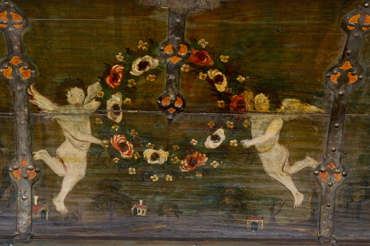 Kiste med buet lokk og gjennombrudte jernbeslag og bånd. Utvendig ådret og med initialer og årstall på baksiden. Innvendig bemalt med to engler og små hus i lokket.