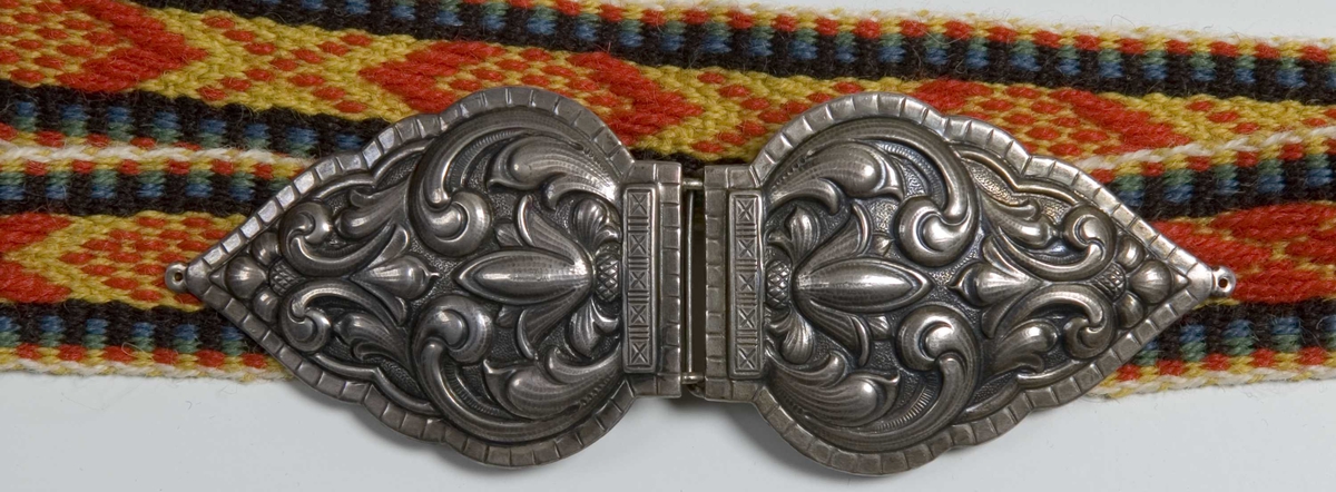 Smalt vevd belte som lukkes med spenne. Samme type bånd som på stakken til kvinnebunad fra vestfold 1956-modell.